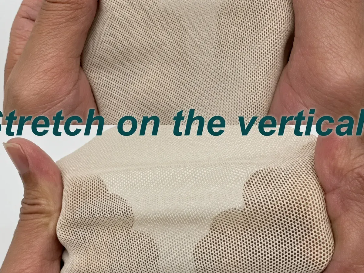 Hands stretching a compression fabric panel, showing vertical stretch