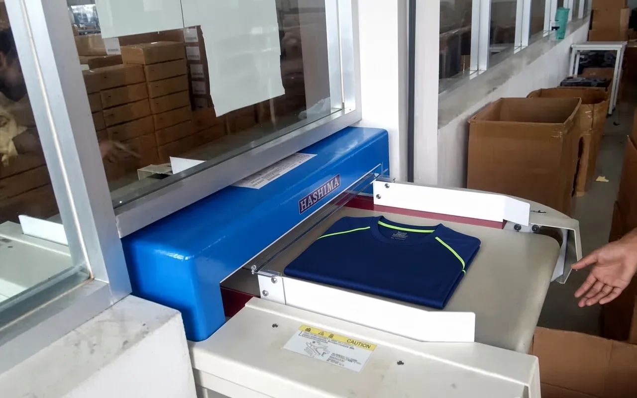 Conveyor metal detector inspecting finished garments for broken needles