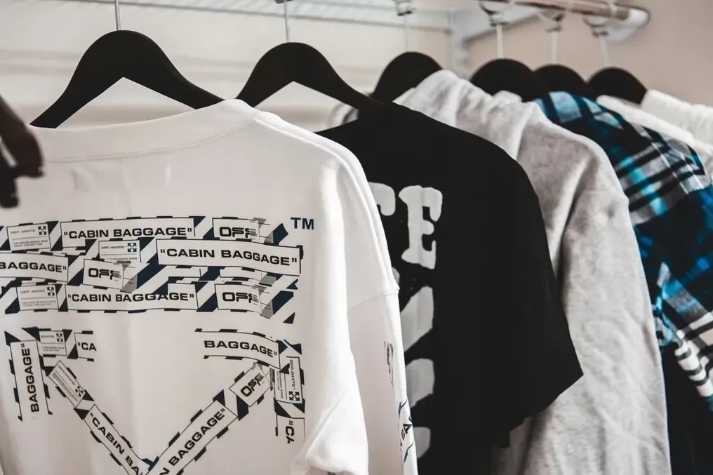 Range of custom printed t-shirts and hoodies hanging on a rack showing different all-over designs