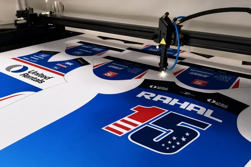 Laser cutting machine cutting printed garment panels from a sublimation printed sheet