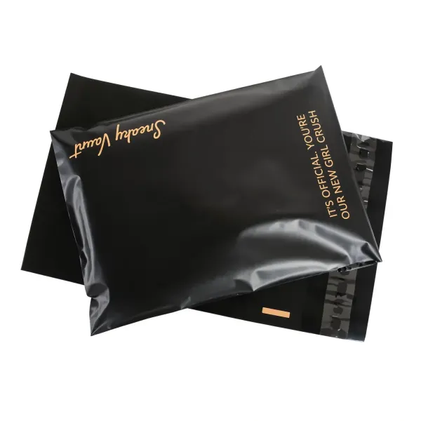 Two printed matte black poly mailers with a copper brand logo