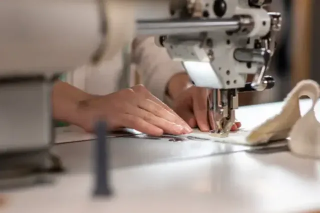 Operator sewing a garment on an industrial machine in a cut and sew factory