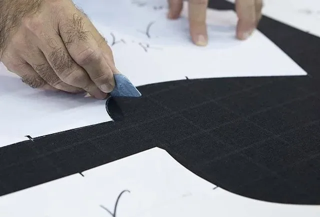 Tailor taking custom cut and sew measurements to the pattern